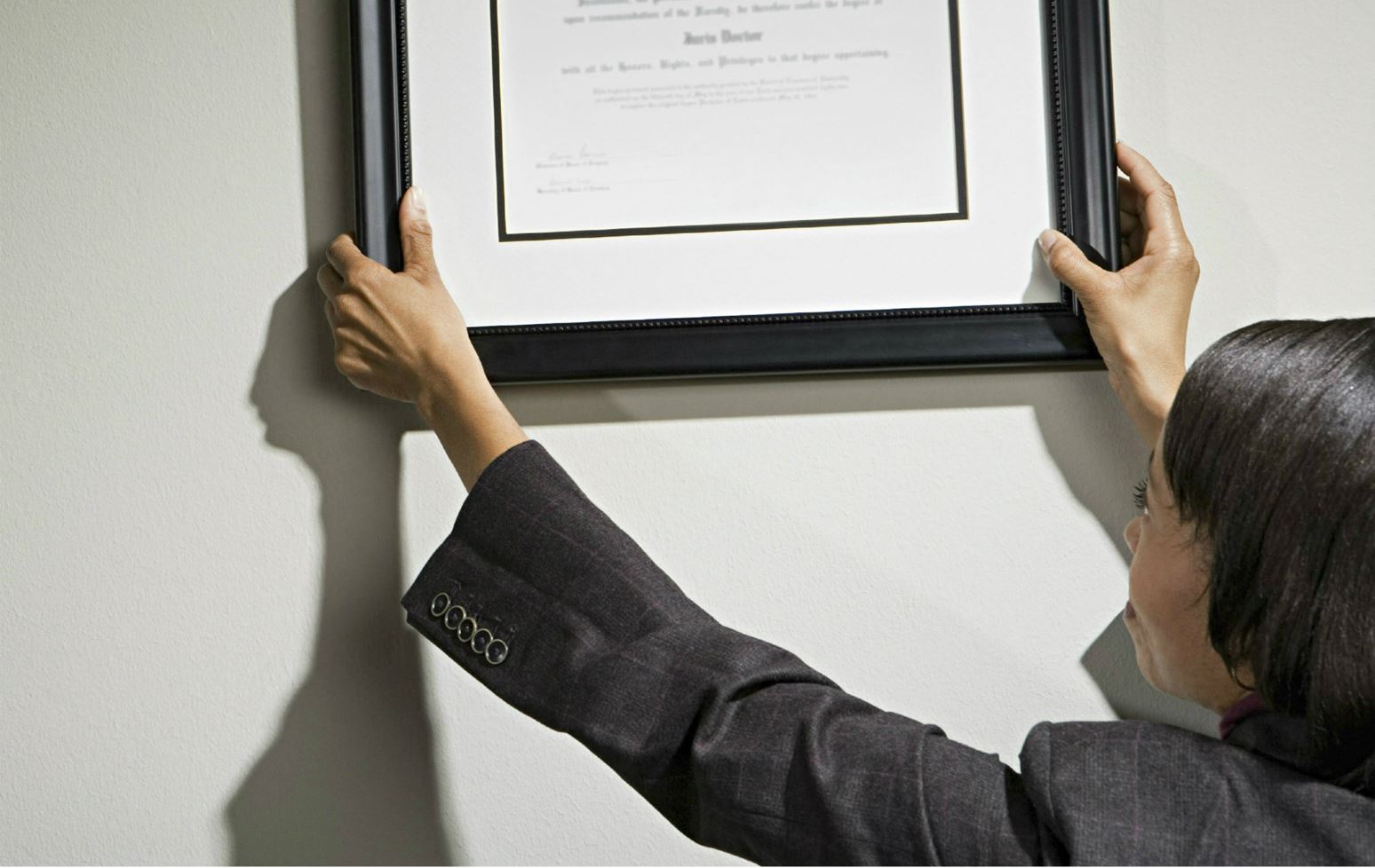Woman hanging certificate on office wall