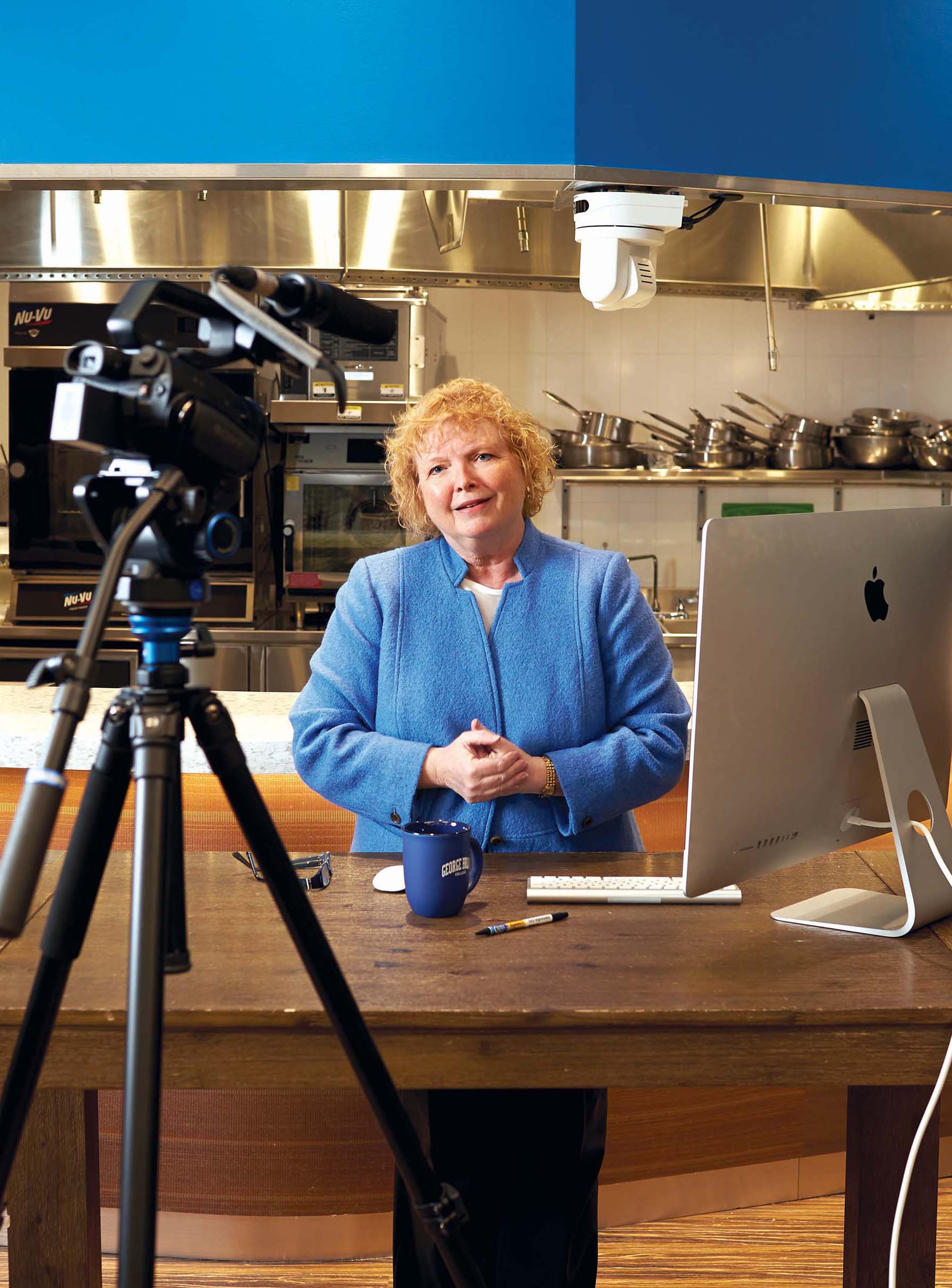 Lorraine Trotter in blue dress in front of video camera and computer
