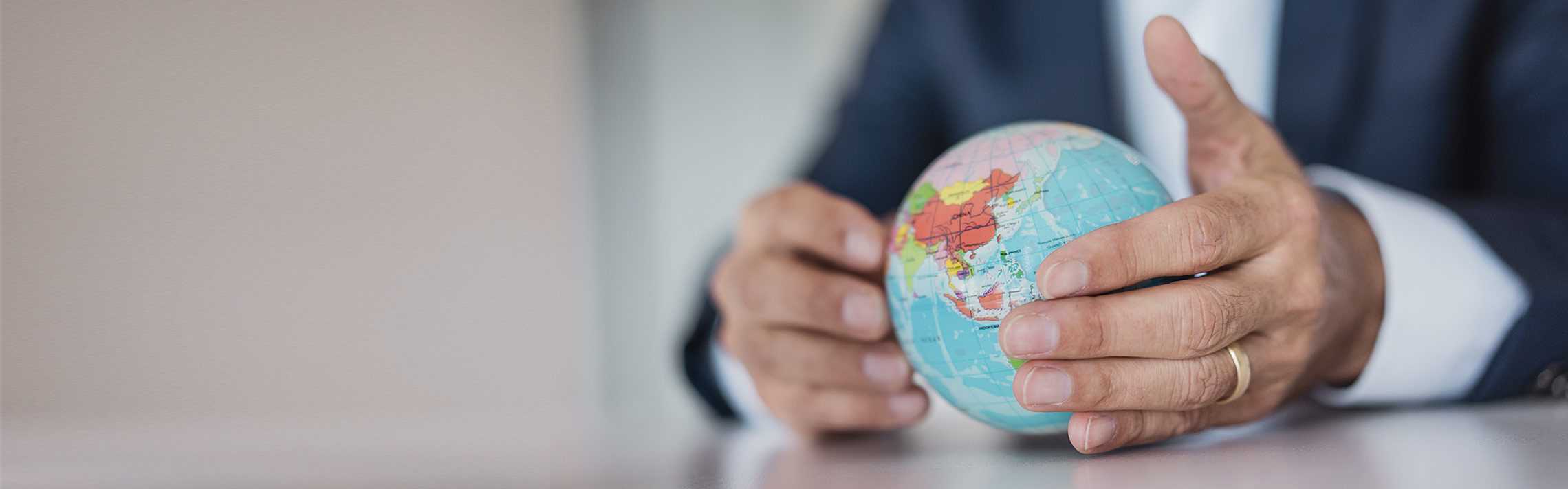 Close-up of hands of businessman holding globe.