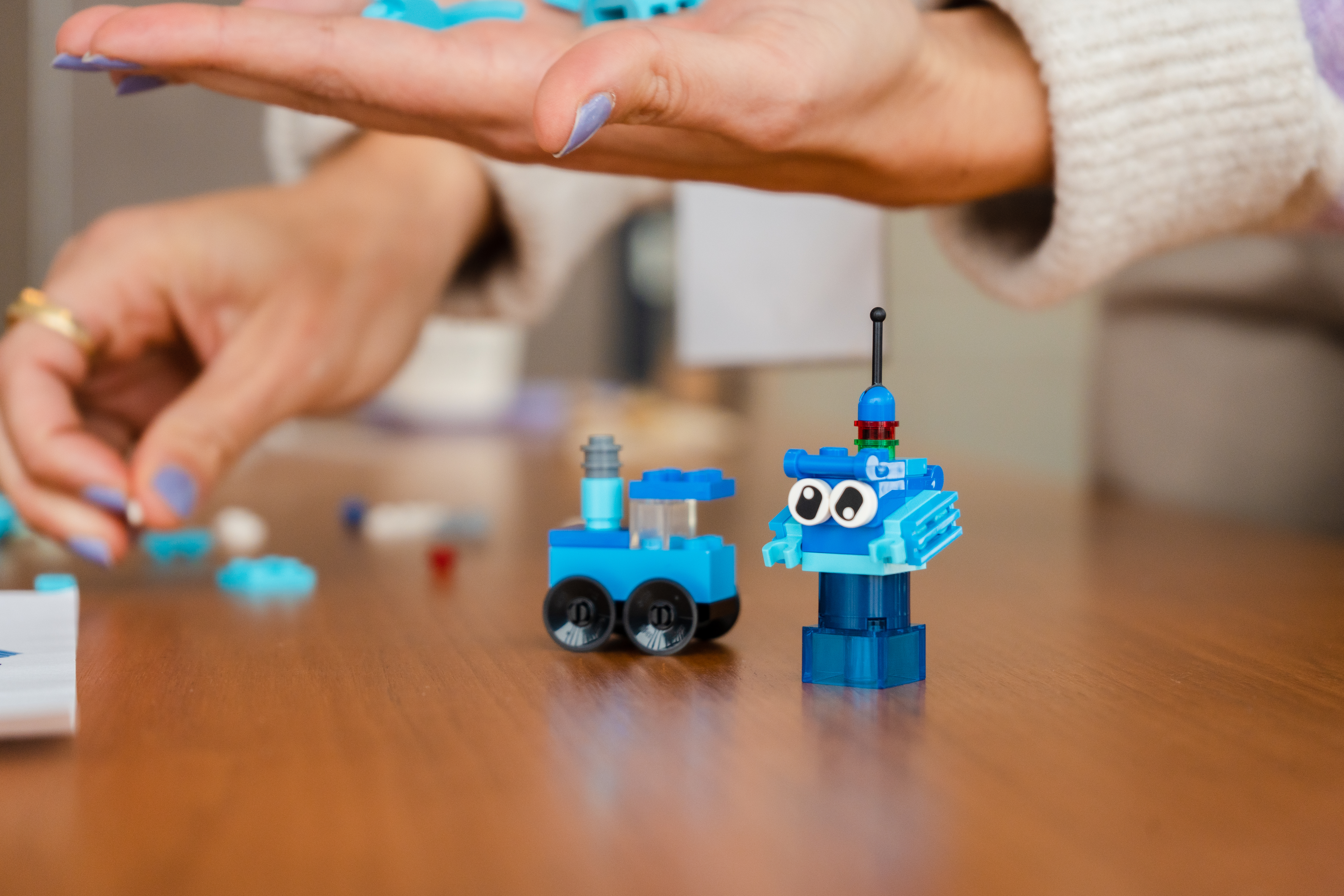 Photo of participant holding Lego pieces, with two built small structures in the foreground