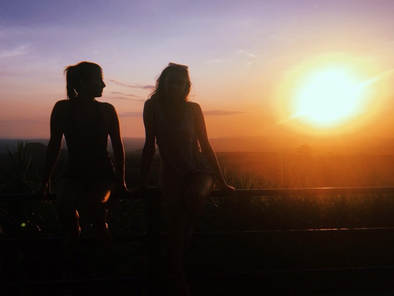 Paula and Mia sitting on a fence at sunset