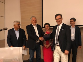 Dr. Athanassakos receives the award from a member of the Board of Trustees of the Multinational Finance Society
