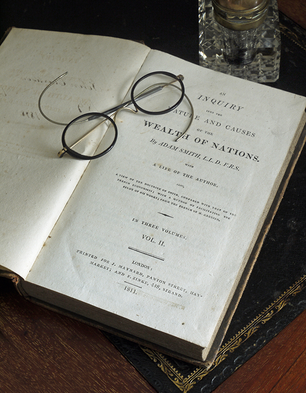 A picture of some old glasses sitting on The Wealth of Nations book