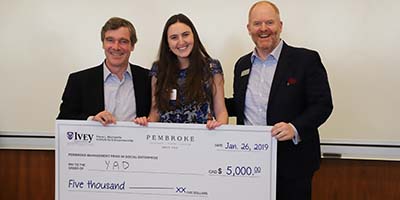 Three people holding a cheque