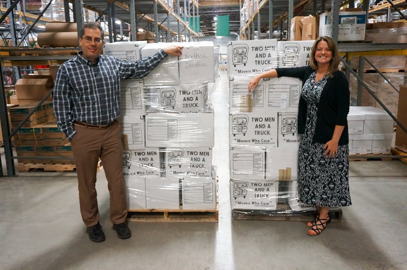 A man and a woman standing beside some packaged shipping boxes
