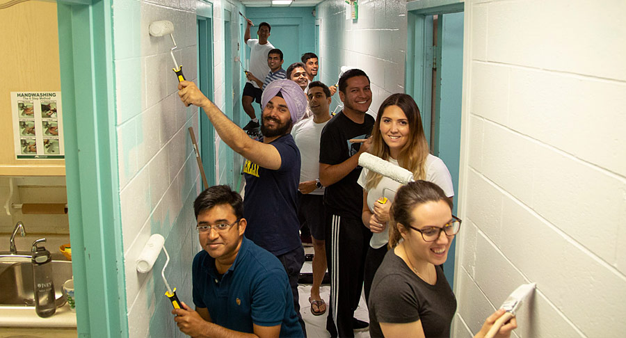 A group of students painting the walls in a hallway