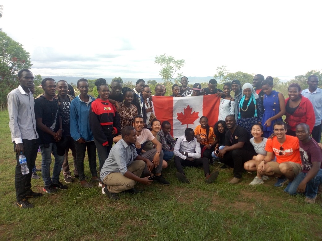 A large group of students posing together holding a Canadian flag