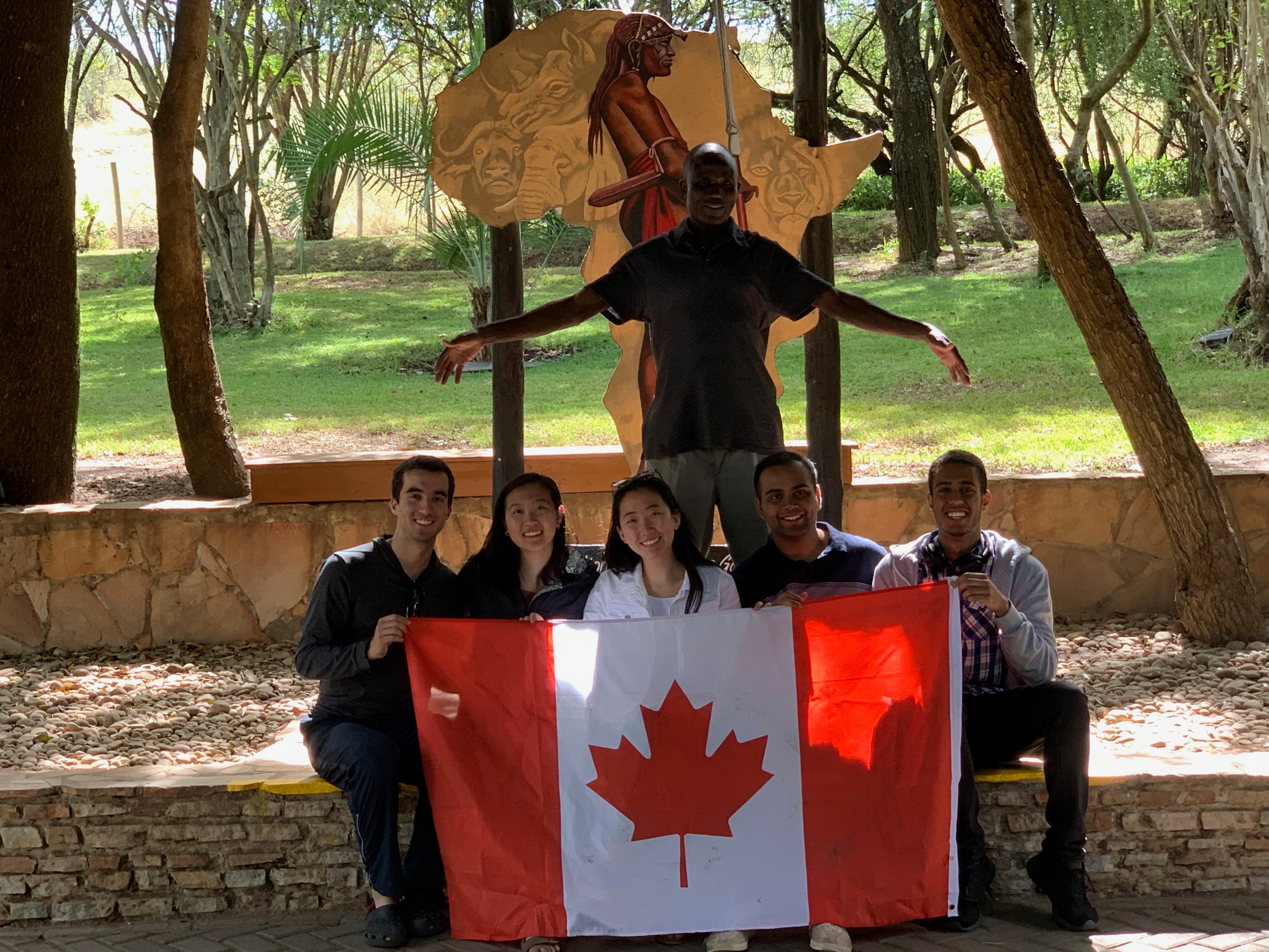 Students posing together holding a Canadian flag
