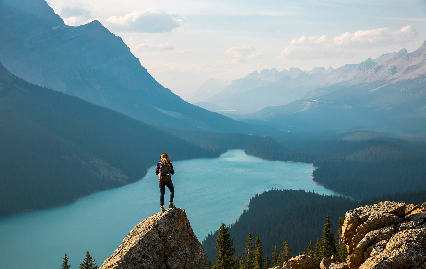 A hiker atop a mountain overlooking a lake
