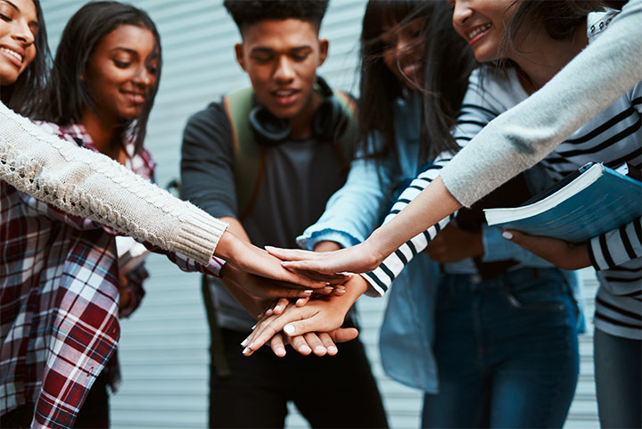 A group of students stacking their hands in the middle.