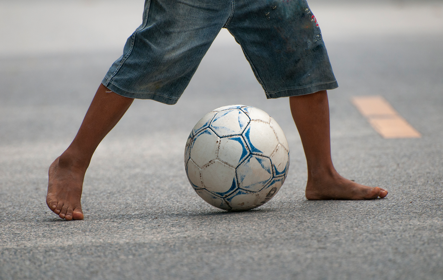 Child In Bare Feet Kicking Soccer Ball