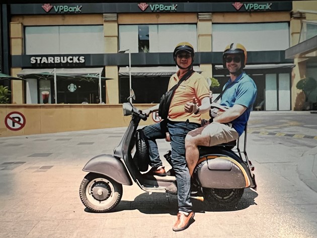 2 men riding a vespa in vietnam