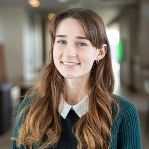 Kirsten Swatuk stands in front of blurred Ivey hallway, smiling.
