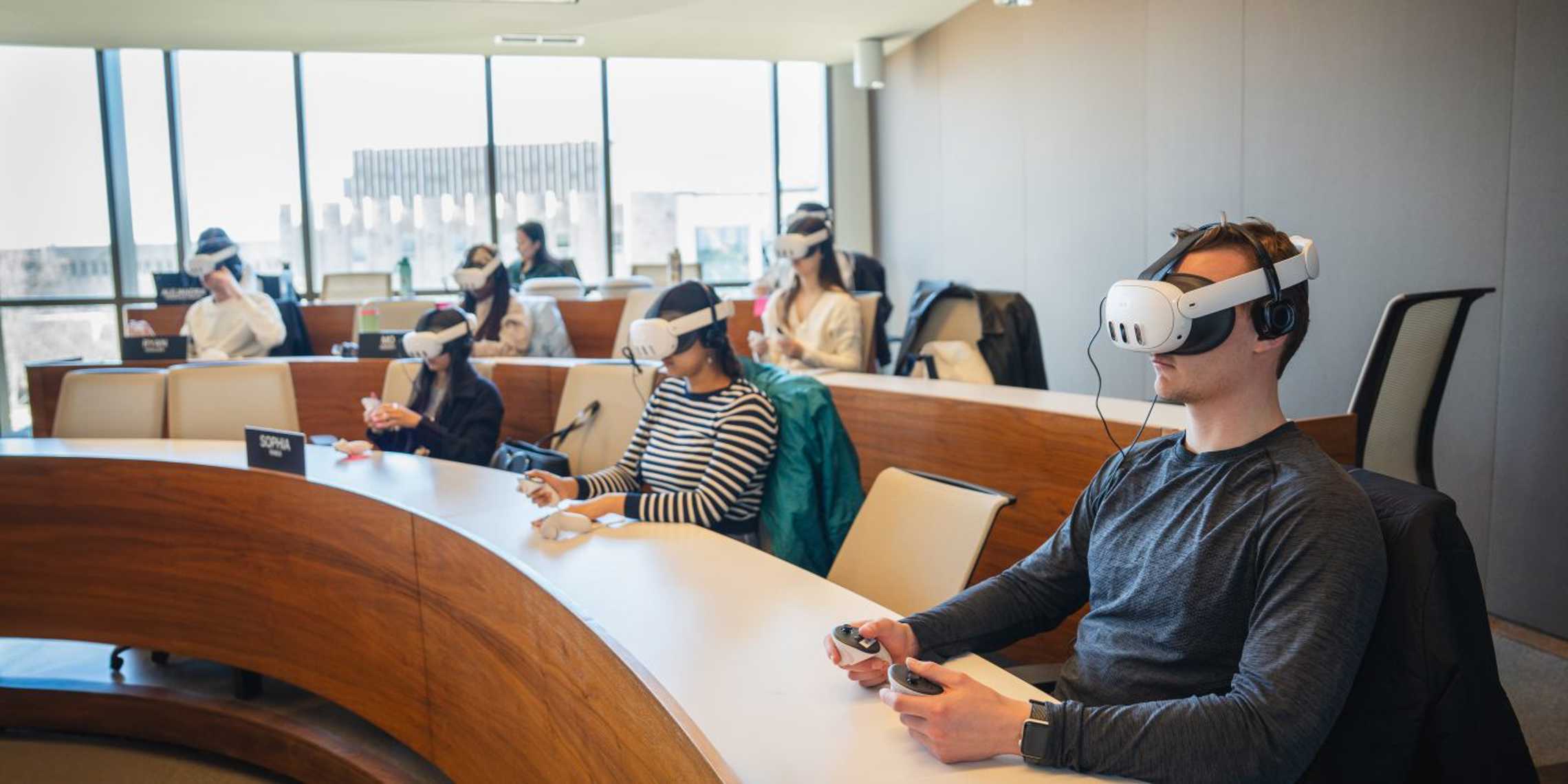 A group of university students wearing VR headsets in a tiered Ivey classroom