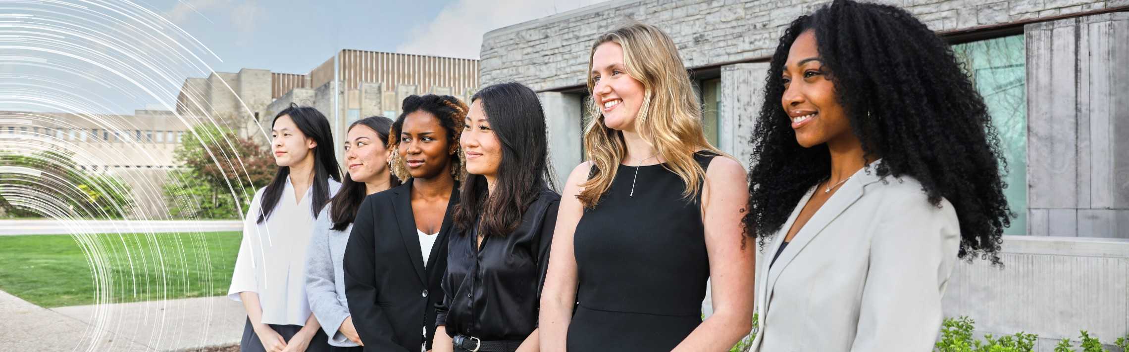 Portrait of smiling university student standing in front of donor names on a wall.