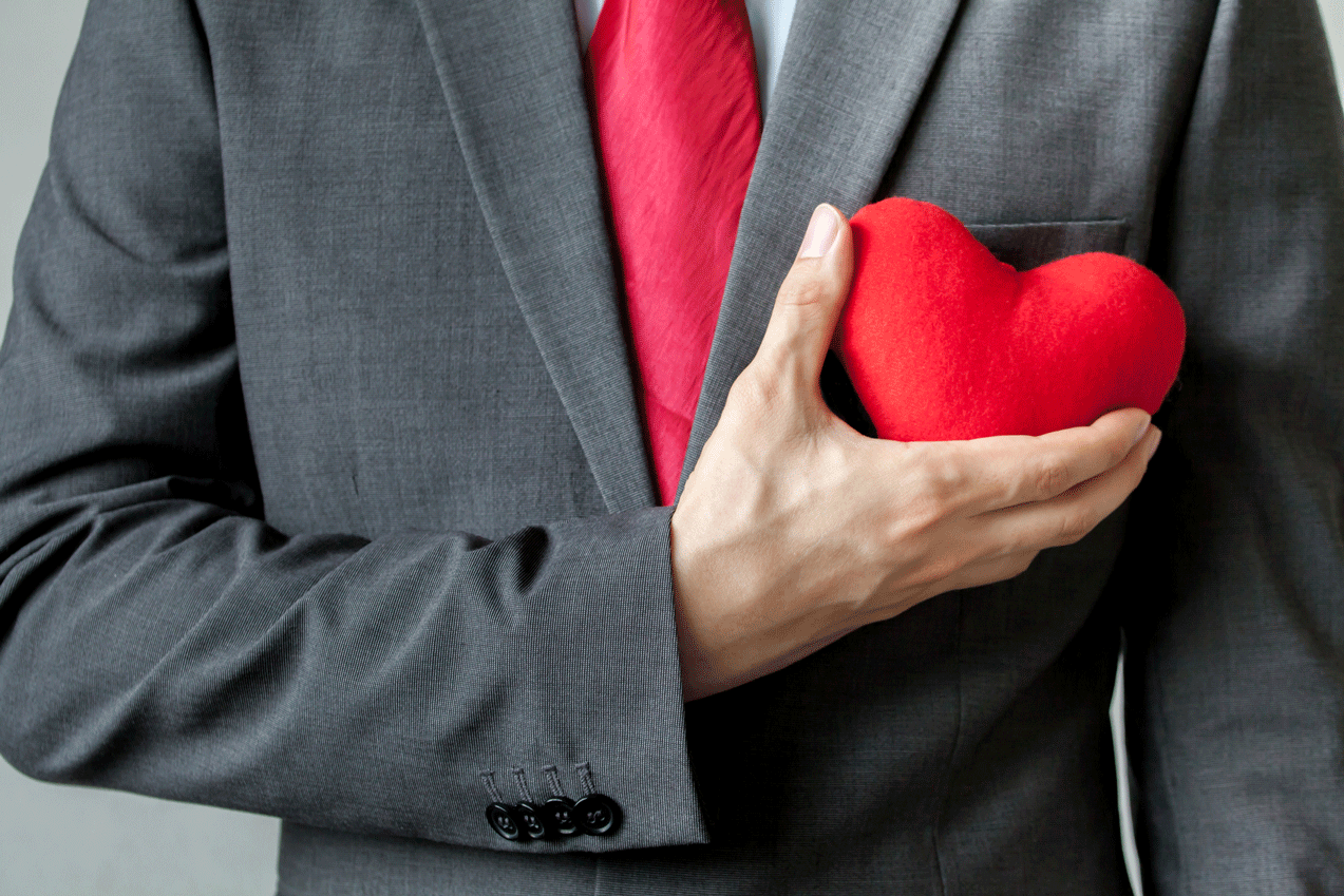 Businessman holding plush heart over chest